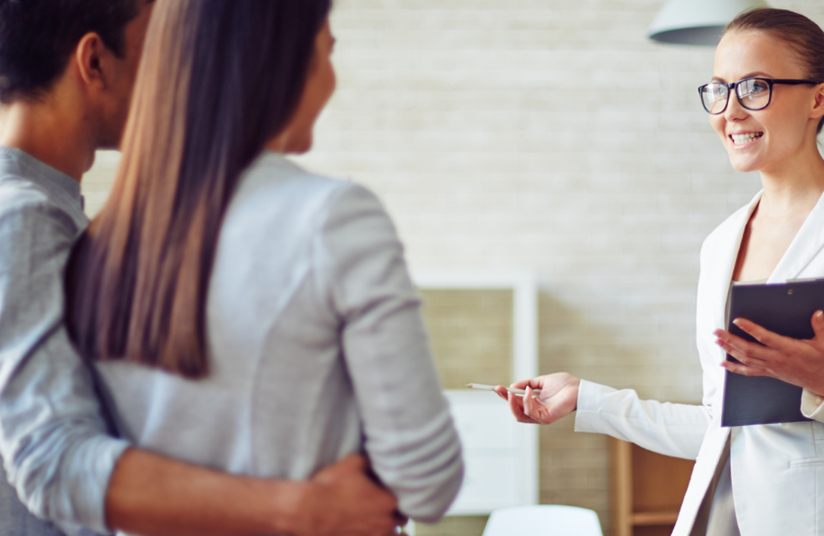 Couple with arms around each other talking to a female property manager